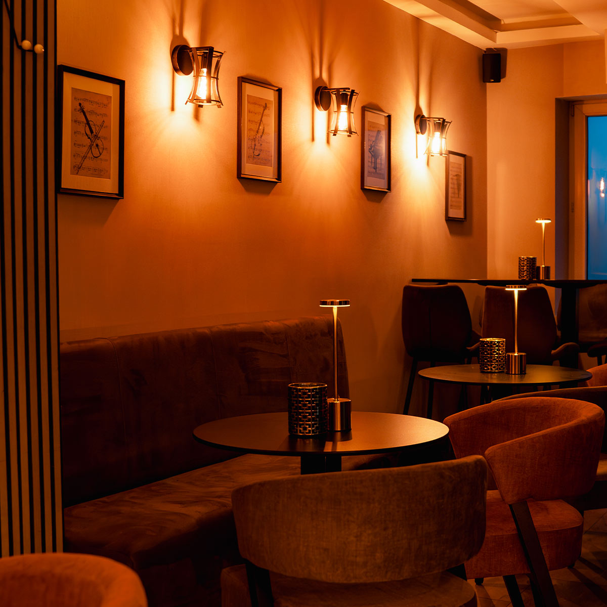 Gemütliches Café mit warmem Licht, runden Tischen und stilvollen Sitzgelegenheiten.