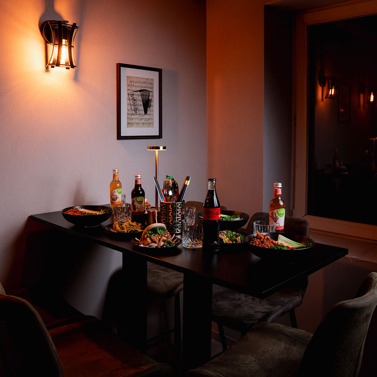 Dunkler Tisch voller Speisen und Getränke, stimmungsvolle Beleuchtung, gemütliche Atmosphäre.